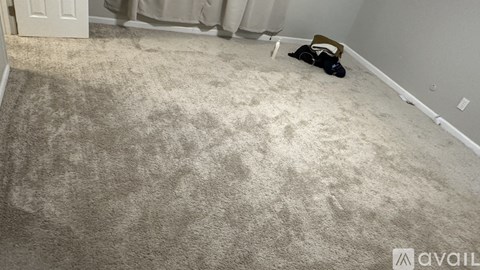 A room with a carpet and a person lying on the floor.