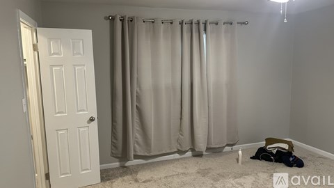 A bathroom with a white door and a beige shower curtain.