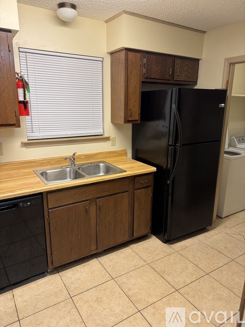 A kitchen with a black refrigerator and wooden cabinets.