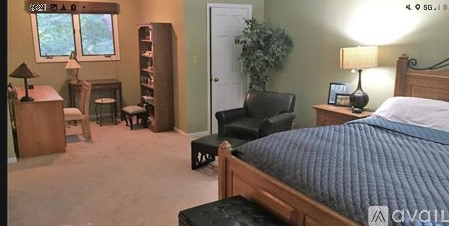 A bedroom with a bed, chair, and lamp.