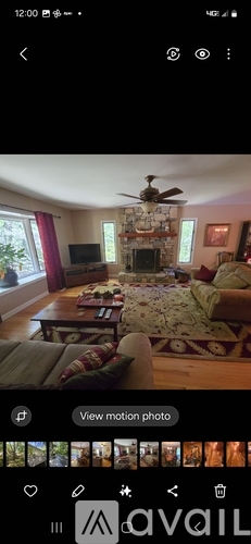 A living room with a fireplace and a ceiling fan.