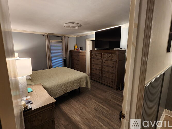 A bedroom with a bed, dresser, and a window with blinds.