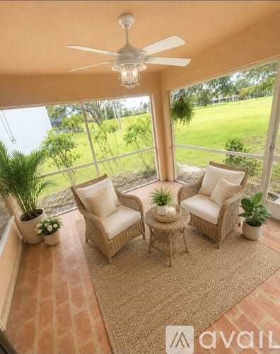 A patio with a fan, two chairs and a table.