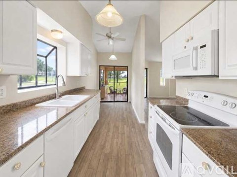 A kitchen with white cabinets and a brown countertop.