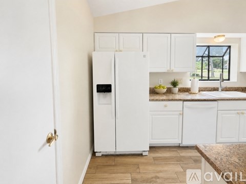 A kitchen with white cabinets and a white fridge.