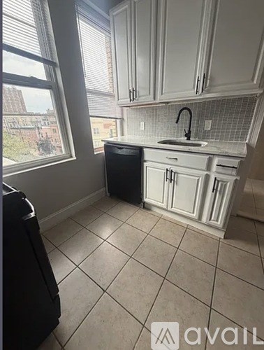 A kitchen with white cabinets and a black trash can.