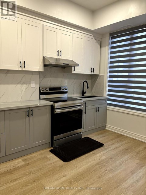 A kitchen with white cabinets and a black mat on the floor.