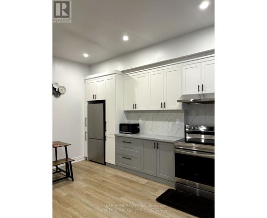 A kitchen with white cabinets and a marble backsplash.