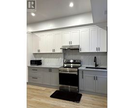 A modern kitchen with white cabinets and a black stove top oven.