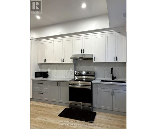 A modern kitchen with white cabinets and a black stove top oven.