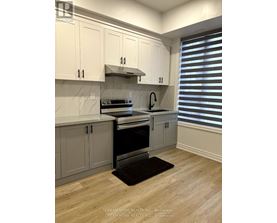 A kitchen with white cabinets and a black mat on the floor.