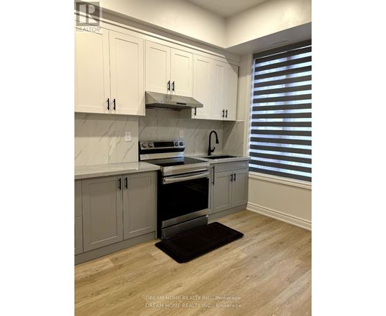 A kitchen with white cabinets and a black mat on the floor.