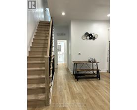 A hallway with a staircase and a table with a phone on it.