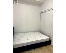 A bed with a white sheet and green palm tree pattern is in a room with a white wall and a door.