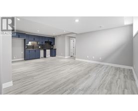 A spacious room with a kitchen area in the background.