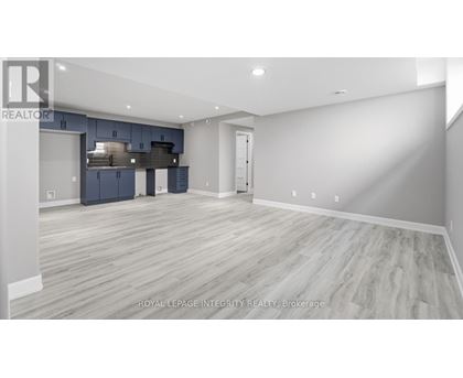 A spacious room with a kitchen area in the background.