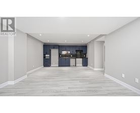 A spacious room with a kitchen area in the background.