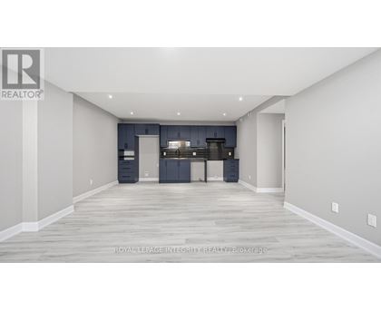 A spacious room with a kitchen area in the background.