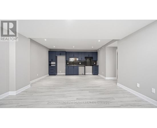 A spacious room with a kitchen area in the background.