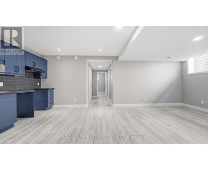 A spacious kitchen with blue cabinets and a white doorway leading to another room.