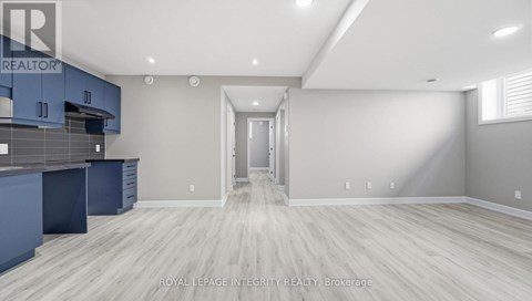 A spacious kitchen with blue cabinets and a white doorway leading to another room.