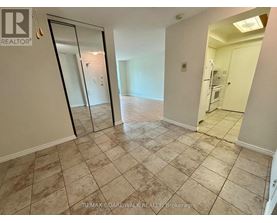A room with a tiled floor and a glass door leading to another room.