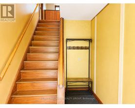 A staircase with a yellow wall and a black railing.