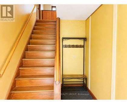 A staircase with a yellow wall and a black railing.