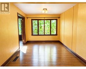 A room with wooden floors and a window with a view of trees.