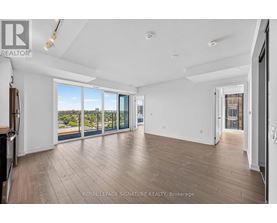 A spacious room with wooden flooring and sliding glass doors leading to a balcony.