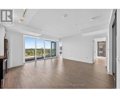 A spacious room with wooden flooring and sliding glass doors leading to a balcony.