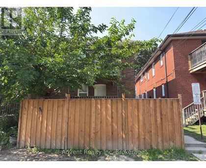 A wooden fence in front of a red brick building.