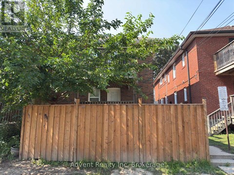 A wooden fence in front of a red brick building.