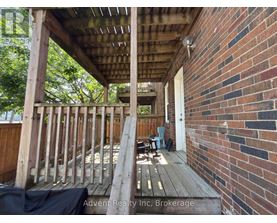 A wooden deck with a brick wall and a doorway.