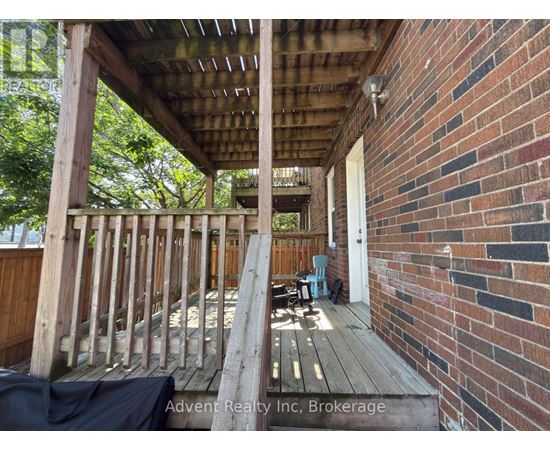 A wooden deck with a brick wall and a doorway.