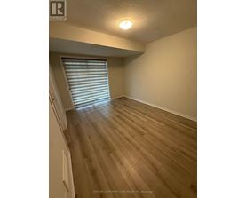 A room with wooden flooring and a window with blinds.