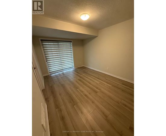 A room with wooden flooring and a window with blinds.