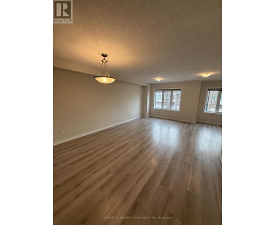 A room with wooden flooring and a pendant light hanging from the ceiling.