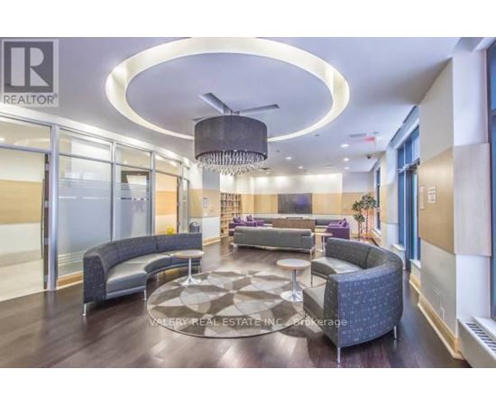 A modern living room with a circular light fixture and a large rug.