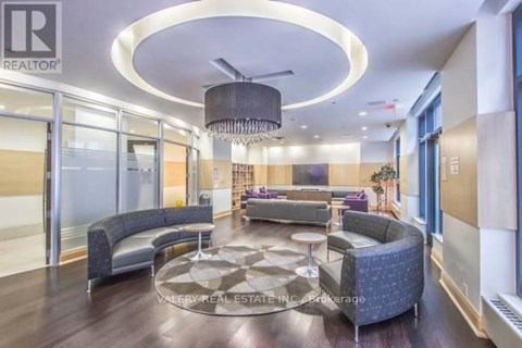A modern living room with a circular light fixture and a large rug.