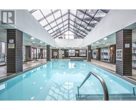A swimming pool inside a building with a glass ceiling.