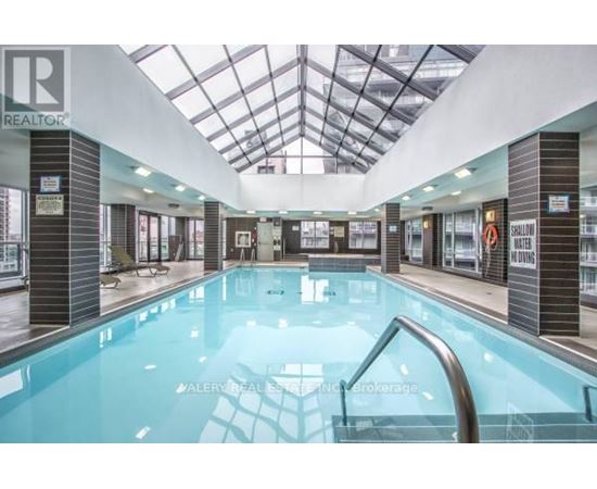 A swimming pool inside a building with a glass ceiling.