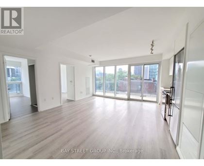 A spacious room with wooden flooring and large windows.