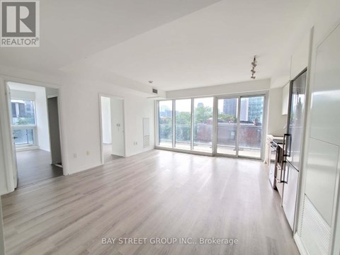 A spacious room with wooden flooring and large windows.