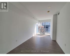 A spacious room with wooden floors and a large window.