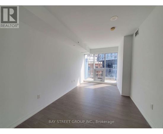 A spacious room with wooden floors and a large window.