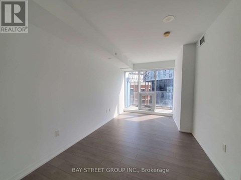 A spacious room with wooden floors and a large window.