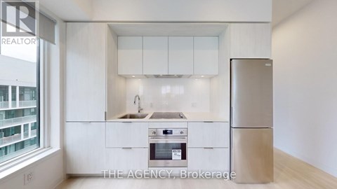 A kitchen with white cabinets and a refrigerator.