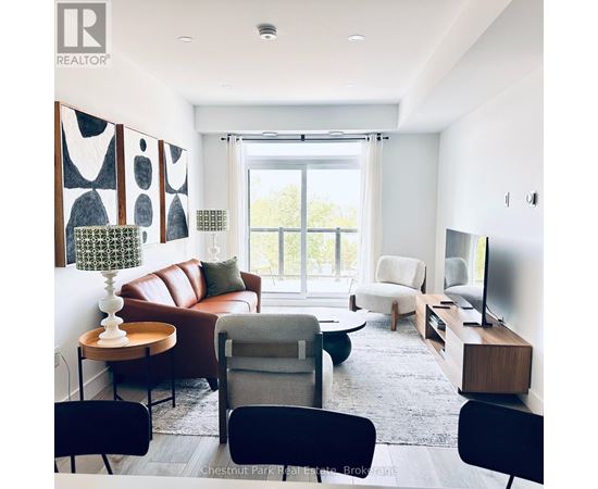 A living room with a brown leather couch, a grey armchair, a wooden side table, and a television.