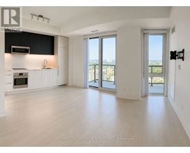 A spacious, empty room with a view of the city through large windows.